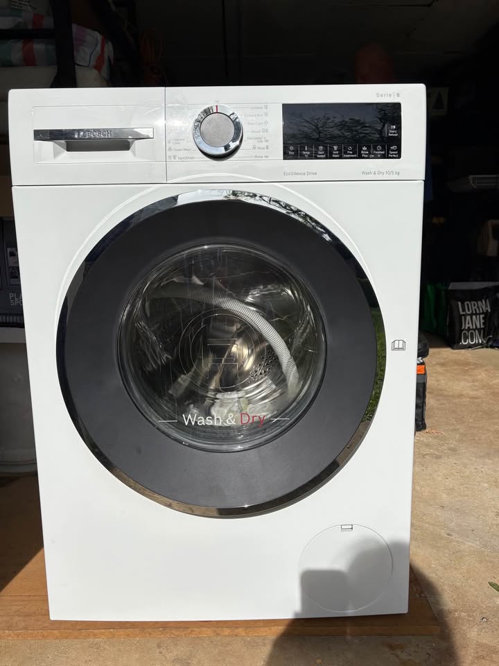 Front view of a Bosch Serie 6 10.5/6 kg front-load washer dryer ( WNA2E4U1IN), control panel with dial and buttons above a large circular glass door with a hose visible inside. 
